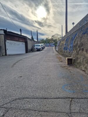 Zufahrtsstraße zur Rappachgasse 26 mit leichter Steigung und unebenem Asphalt.